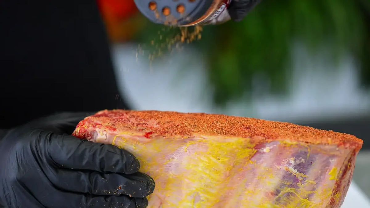 The seasoning. Adriano applying Xtra Mojo to mustard-coated beef ribs