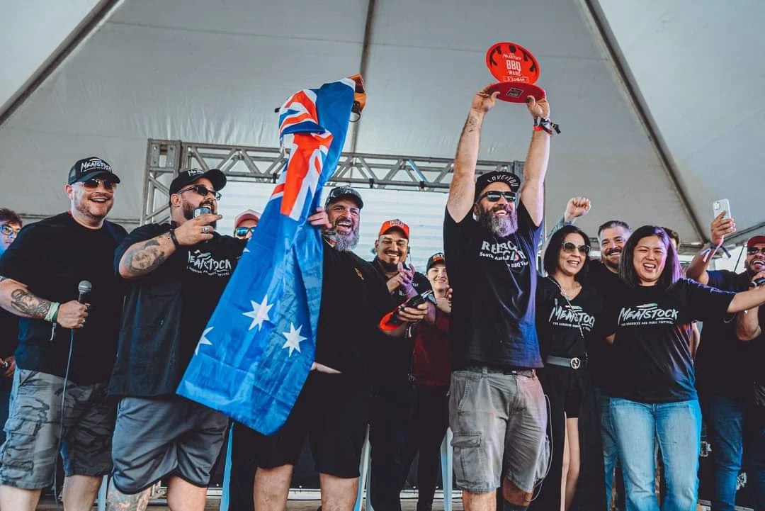 Adriano Andrade raising a red trophy above his head during a celebration on the Meatstock stage